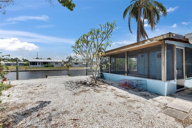 view of home's exterior with a sunroom and a water view
