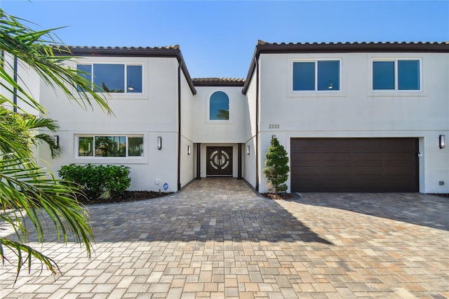 2233 Donato Dr, Belleair Beach, FL 33786 - mediterranean / spanish-style house featuring an attached garage, stucco siding, a tiled roof, and driveway