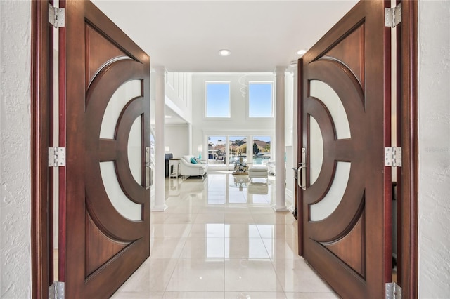 2233 Donato Dr, Belleair Beach, FL 33786 - foyer entrance with decorative columns, a towering ceiling, recessed lighting, a textured wall, and light tile patterned floors