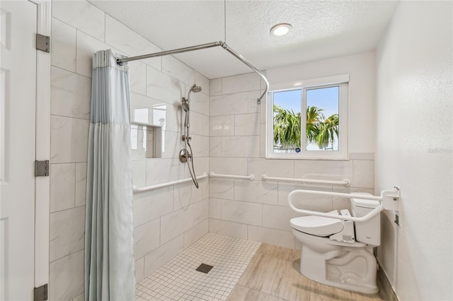 2233 Donato Dr, Belleair Beach, FL 33786 - bathroom with tile walls, a textured ceiling, toilet, a shower stall, and tile patterned floors