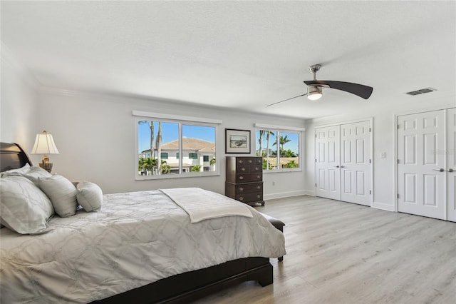 2233 Donato Dr, Belleair Beach, FL 33786 - bedroom featuring visible vents, two closets, light wood-style flooring, crown molding, and ceiling fan