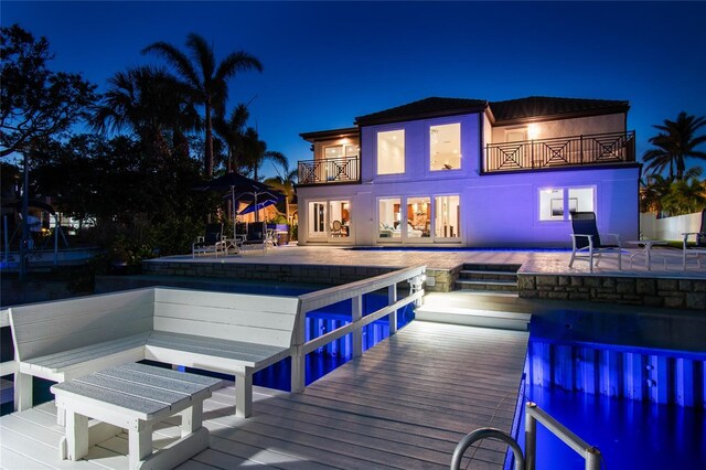 2233 Donato Dr, Belleair Beach, FL 33786 - back of house at twilight with a balcony, a patio, and an outdoor pool