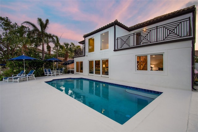 2233 Donato Dr, Belleair Beach, FL 33786 - rear view of house featuring a balcony, a patio, an outdoor pool, and stucco siding