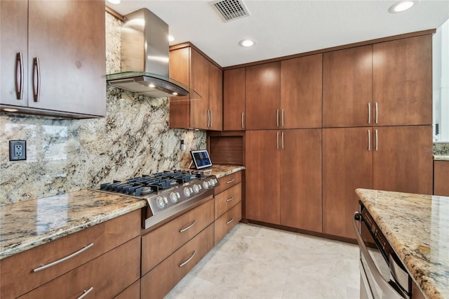 2233 Donato Dr, Belleair Beach, FL 33786 - kitchen with stainless steel gas stovetop, light stone counters, visible vents, decorative backsplash, and wall chimney exhaust hood