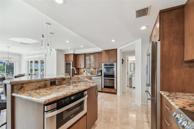 2233 Donato Dr, Belleair Beach, FL 33786 - kitchen with a sink, brown cabinets, visible vents, pendant lighting, and appliances with stainless steel finishes