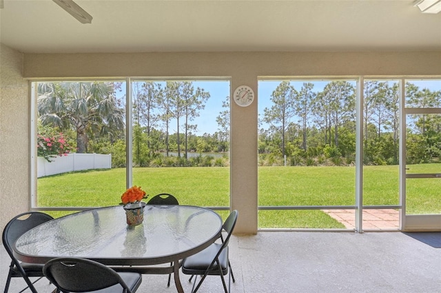 sunroom / solarium with outdoor dining area, ceiling fan, a wealth of natural light, and a water view