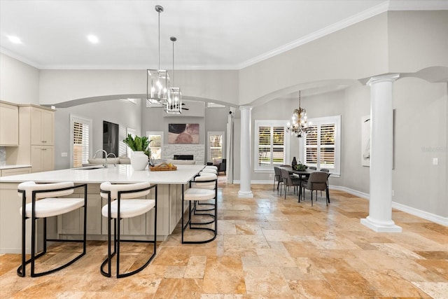 1600 Magnolia Rd, Belleair, FL 33756 - kitchen featuring ornate columns, stone tile flooring, crown molding, light countertops, and a kitchen bar