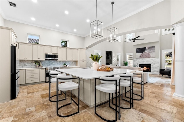 1600 Magnolia Rd, Belleair, FL 33756 - kitchen featuring appliances with stainless steel finishes, stone tile floors, a high ceiling, light countertops, and a sink