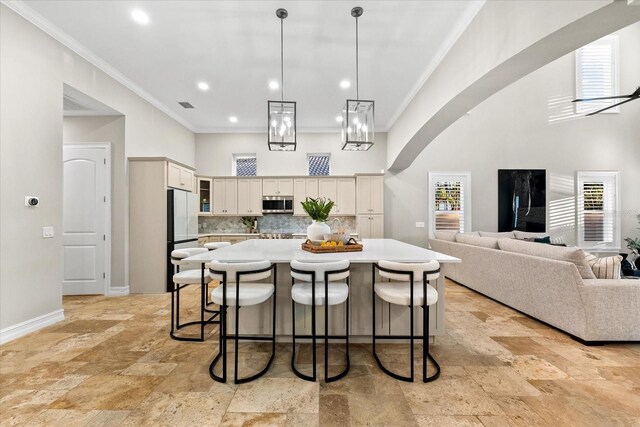 1600 Magnolia Rd, Belleair, FL 33756 - kitchen featuring stainless steel microwave, white fridge, stone tile floors, ornamental molding, and a kitchen bar