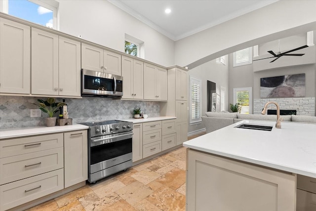 1600 Magnolia Rd, Belleair, FL 33756 - kitchen with appliances with stainless steel finishes, open floor plan, ornamental molding, a sink, and ceiling fan