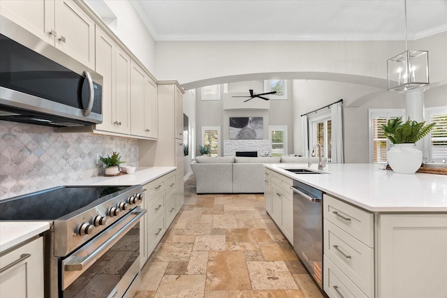 1600 Magnolia Rd, Belleair, FL 33756 - kitchen with stainless steel appliances, a ceiling fan, arched walkways, stone tile floors, and crown molding