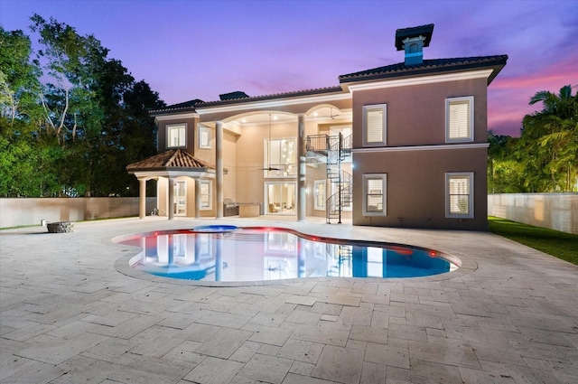 1600 Magnolia Rd, Belleair, FL 33756 - back of house at dusk featuring stairs, a patio area, a jacuzzi, stucco siding, and an outdoor pool