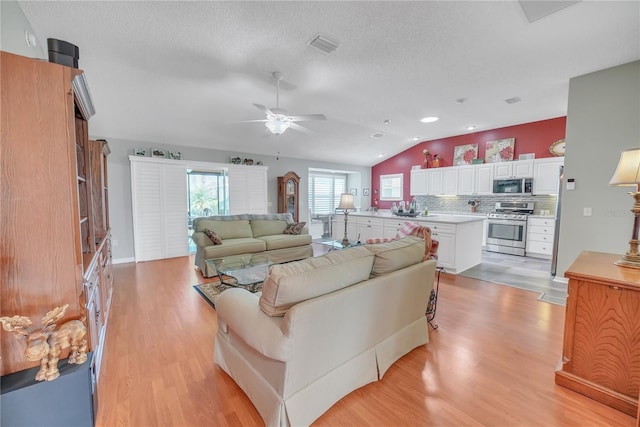 living area featuring recessed lighting, vaulted ceiling, light wood finished floors, visible vents, and a ceiling fan