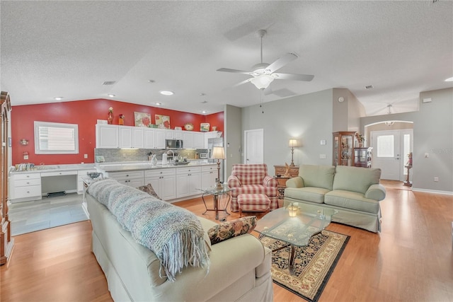 living room with recessed lighting, light wood-style floors, vaulted ceiling, ceiling fan, and a textured ceiling