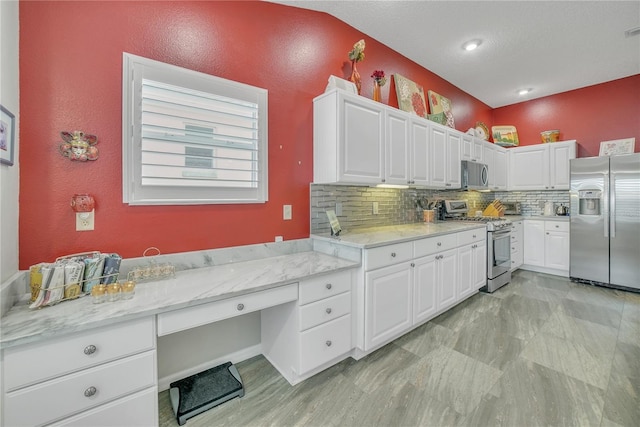 kitchen featuring built in desk, white cabinetry, stainless steel appliances, and tasteful backsplash