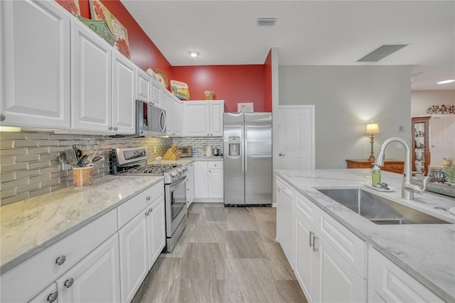 kitchen featuring a sink, visible vents, white cabinetry, backsplash, and appliances with stainless steel finishes