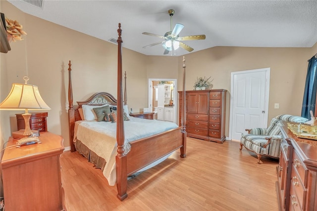 bedroom featuring visible vents, ensuite bath, lofted ceiling, and light wood-type flooring