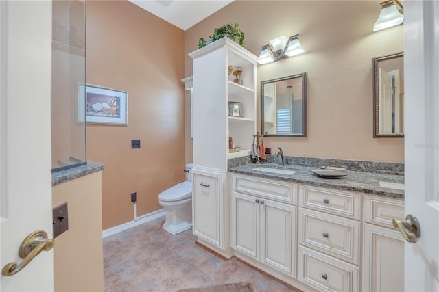 bathroom with toilet, vanity, and baseboards