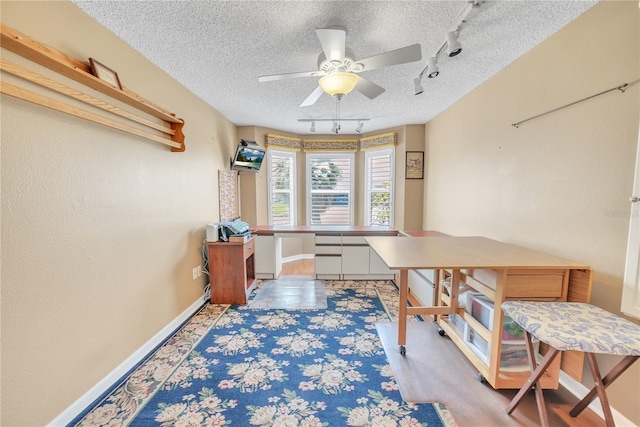 office with baseboards, ceiling fan, rail lighting, and a textured ceiling