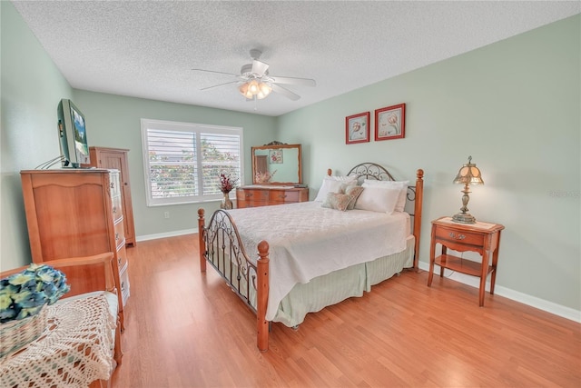 bedroom featuring light wood finished floors, a textured ceiling, ceiling fan, and baseboards