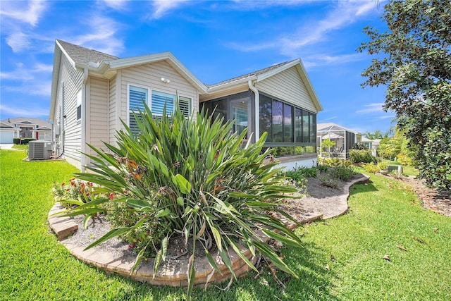 view of property exterior with a sunroom, a yard, and central air condition unit
