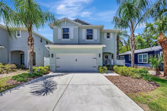 traditional-style home with fence, stucco siding, driveway, and an attached garage