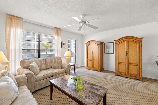 living area featuring a textured ceiling, ceiling fan, light colored carpet, and baseboards