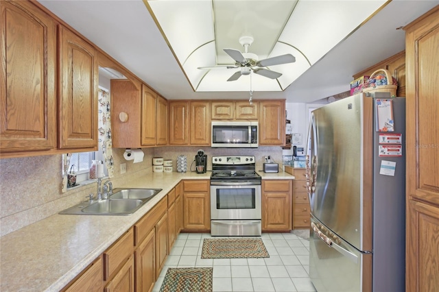 kitchen with light tile patterned floors, stainless steel appliances, light countertops, a sink, and a ceiling fan
