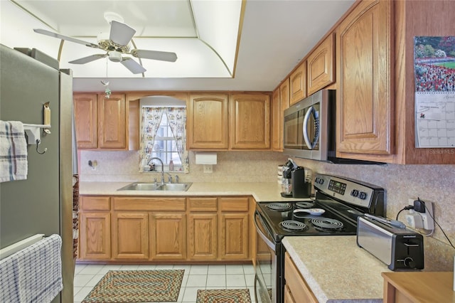 kitchen featuring a sink, decorative backsplash, light tile patterned floors, a ceiling fan, and appliances with stainless steel finishes