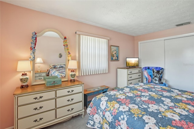 carpeted bedroom featuring a textured ceiling, visible vents, and a closet