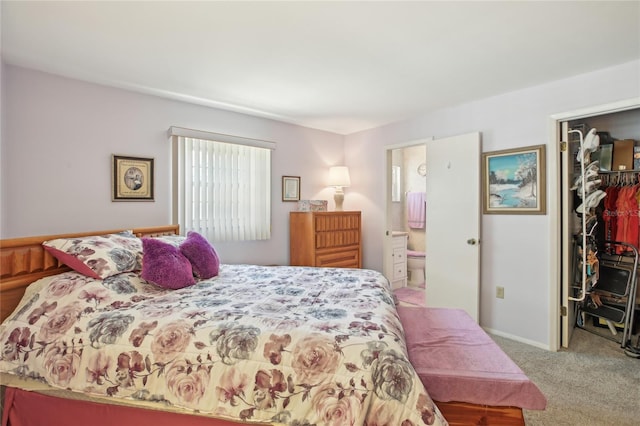 bedroom featuring light colored carpet, a closet, ensuite bath, and a walk in closet