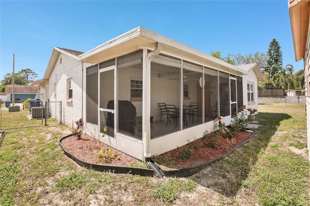 rear view of house with fence, a gate, a lawn, and a sunroom