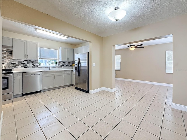 kitchen featuring stainless steel appliances, decorative backsplash, gray cabinets, light countertops, and a textured ceiling