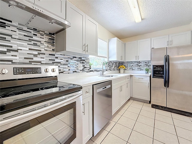kitchen with stainless steel appliances, under cabinet range hood, light countertops, and a sink