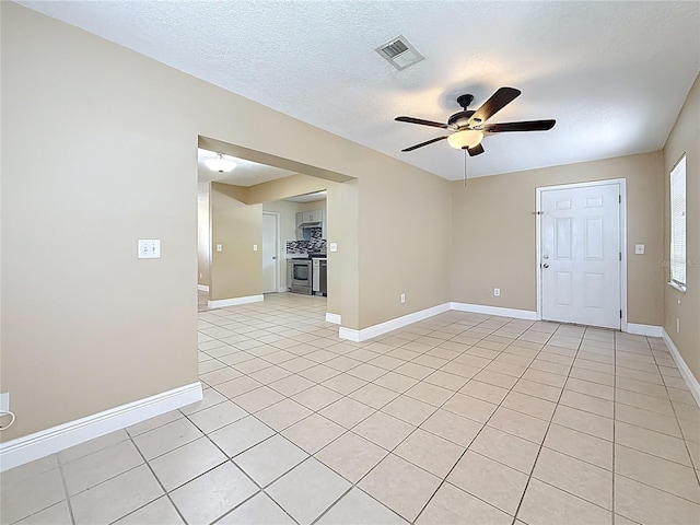 unfurnished room featuring light tile patterned floors, a textured ceiling, visible vents, baseboards, and a ceiling fan