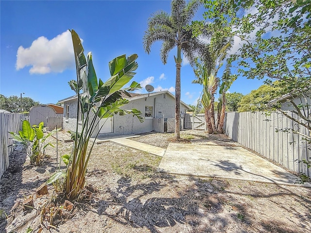 view of yard with a patio area, an outdoor structure, a fenced backyard, a gate, and a storage shed