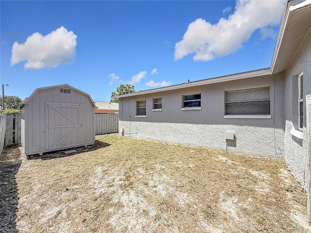 exterior space with fence, a storage shed, and an outbuilding