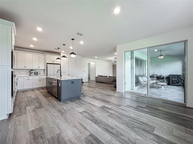 17683 Ramble On Way, Land O Lakes, FL 34638 - kitchen featuring a kitchen island with sink, light countertops, white cabinets, open floor plan, and stainless steel appliances