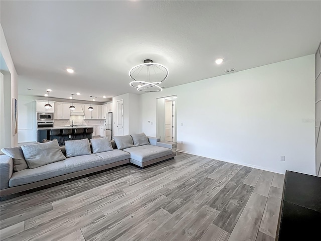 17683 Ramble On Way, Land O Lakes, FL 34638 - living room featuring recessed lighting, a notable chandelier, wood finished floors, and visible vents