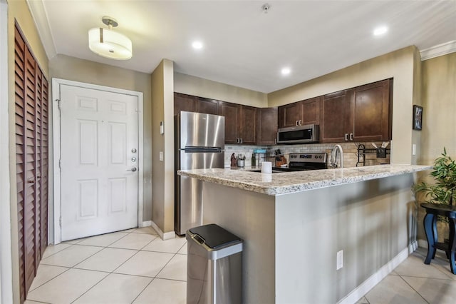 2400 Feather Sound Dr Unit 735, Clearwater, FL 33762 - kitchen with decorative backsplash, dark brown cabinetry, light tile patterned flooring, light stone countertops, and stainless steel appliances