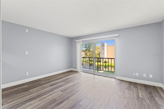 spare room featuring baseboards, a textured ceiling, and wood finished floors