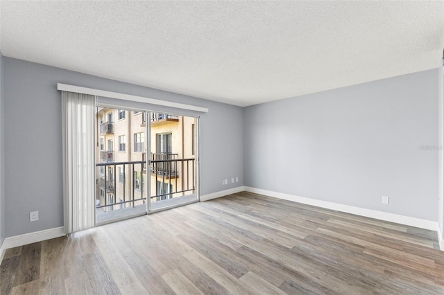 empty room featuring baseboards, a textured ceiling, and wood finished floors