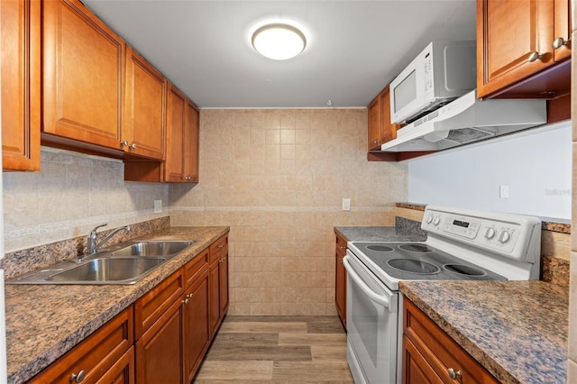kitchen with a sink, white electric stove, brown cabinets, and light wood-style flooring