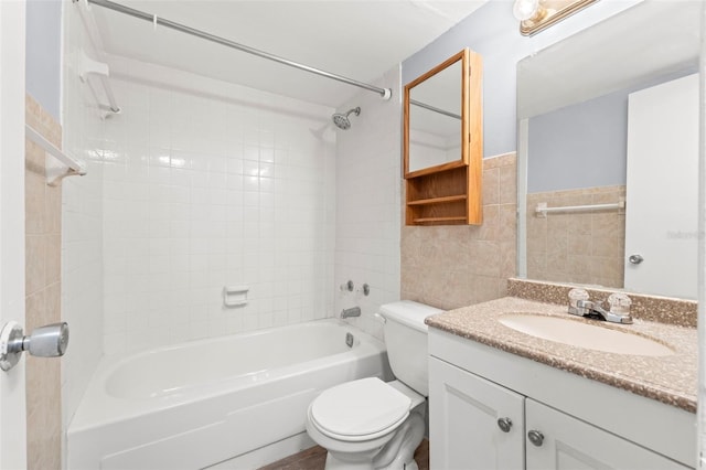 bathroom with tile walls, vanity, toilet, and  shower combination