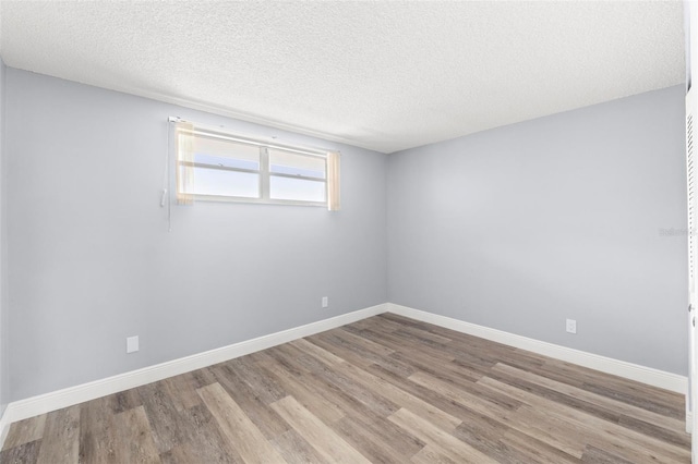 empty room featuring baseboards, a textured ceiling, and wood finished floors