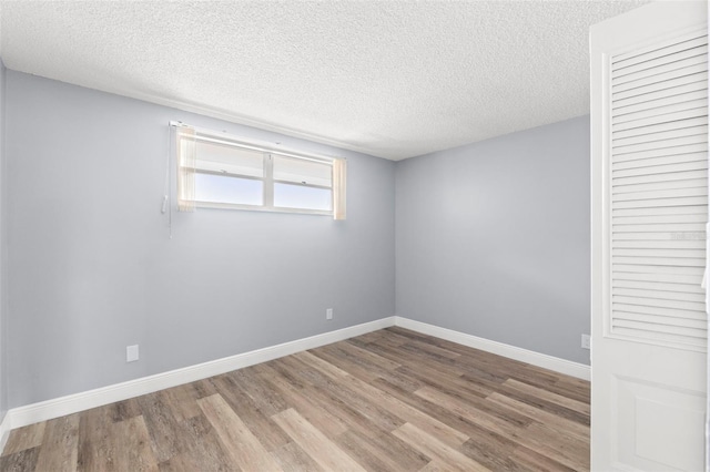 unfurnished room with baseboards, a textured ceiling, and wood finished floors