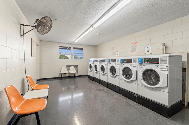 shared laundry area with concrete block wall, a textured ceiling, and washer and clothes dryer