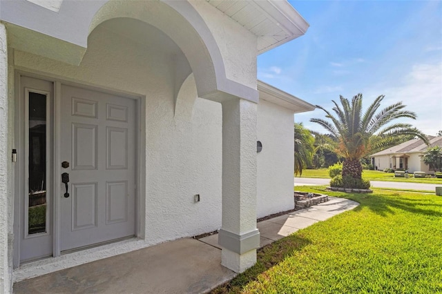 23935 Coral Ridge Ln, Land O Lakes, FL 34639 - view of exterior entry with stucco siding and a yard