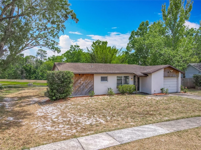 ranch-style house with driveway, a garage, stucco siding, and fence