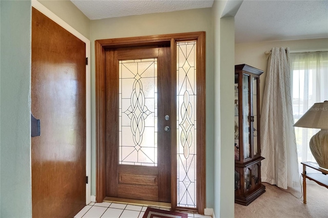 foyer entrance with a textured ceiling and carpet flooring